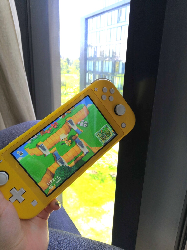 A picture of a yellow nintendo switch lite on which I'm playing Animal Crossing. 