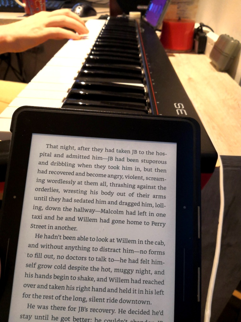 A picture of a kindle and Mikko playing piano in the background