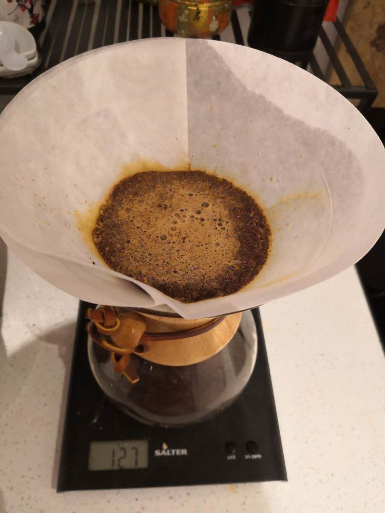 A picture of a chemex coffee maker that is in the midst of brewing some coffee