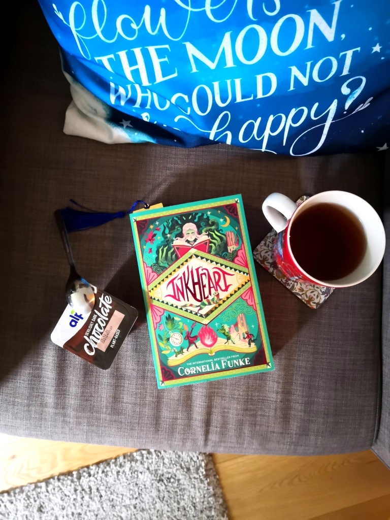 A picture of a chocolate pudding, a cup of tea and Inkheart on a chair