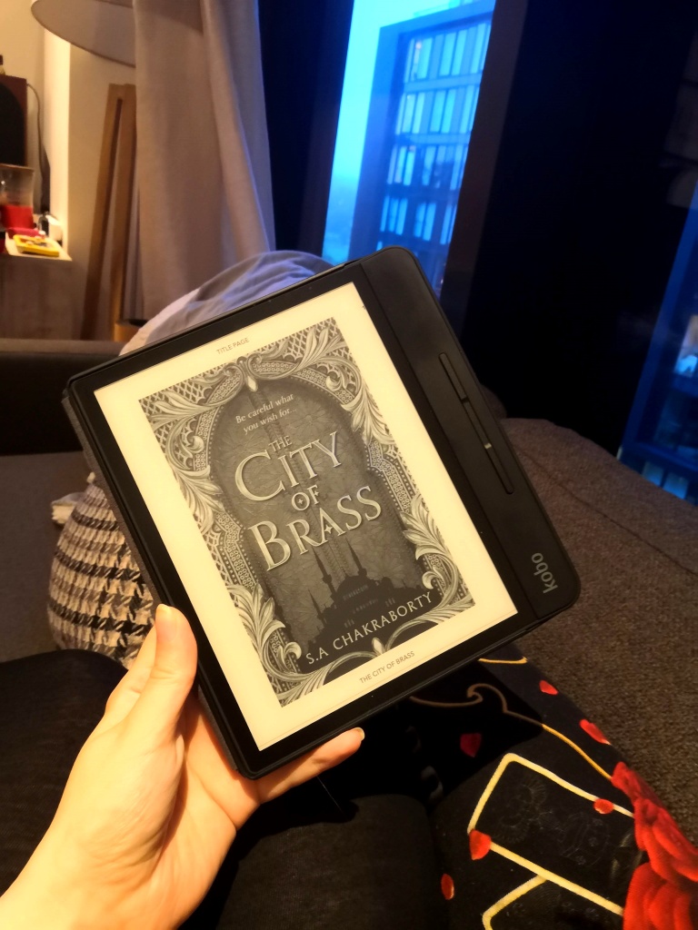 A picture of me holding a Kobo e-reader with The City of Brass on it